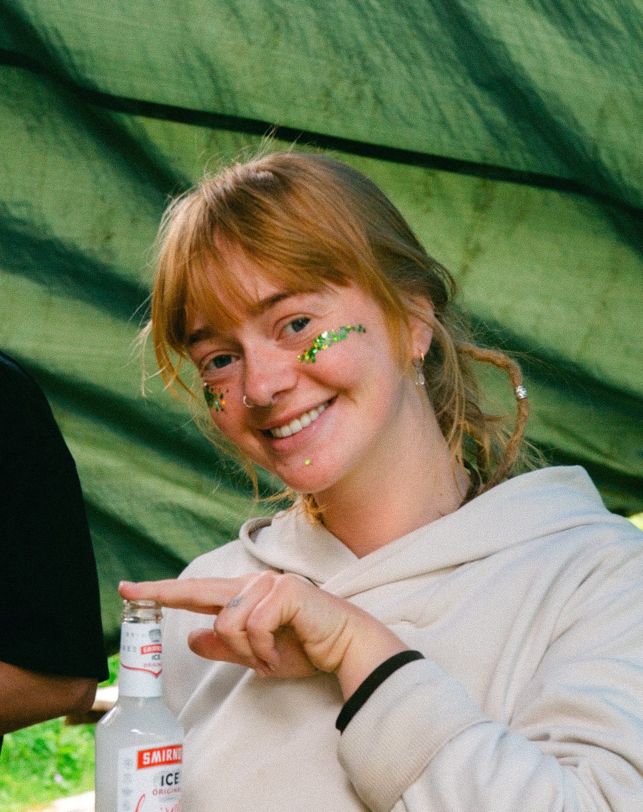 A Estonian woman volunteering at a property during a festival in the Swedish woods, enjoying a drink, smiling and being free.