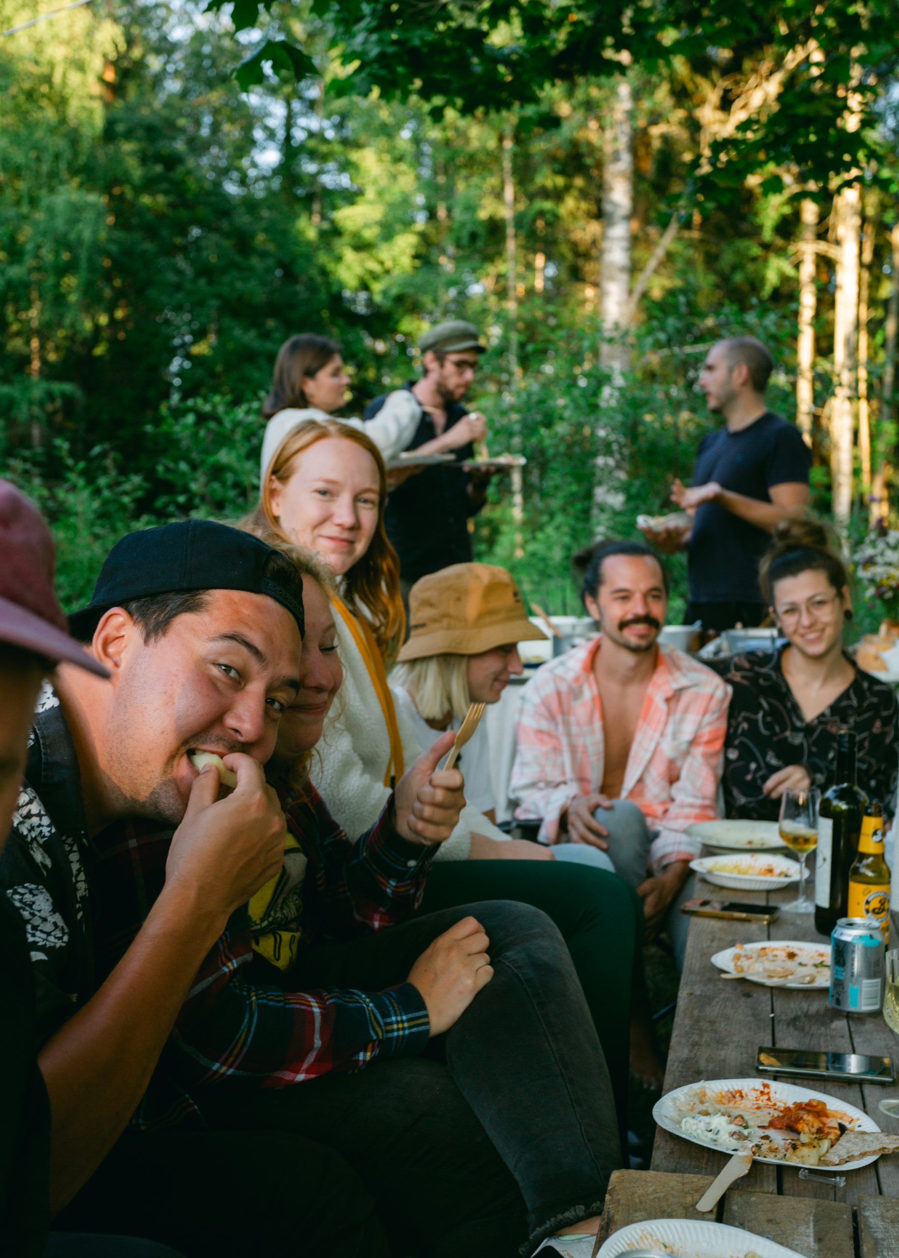 A happy group of volunteers eating a meal together outside in the garden