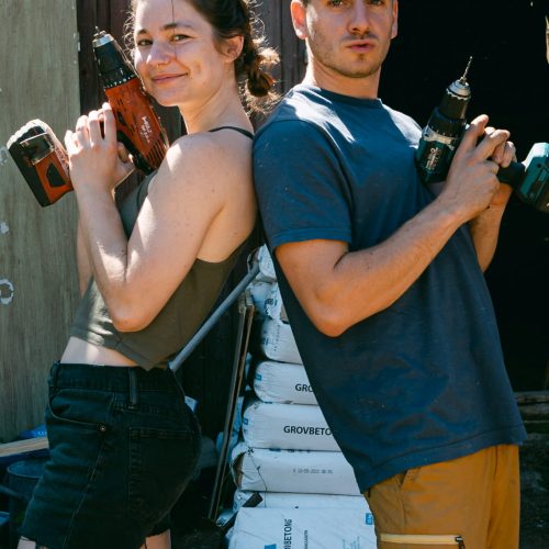 Two volunteers making a funny pose with power tools.